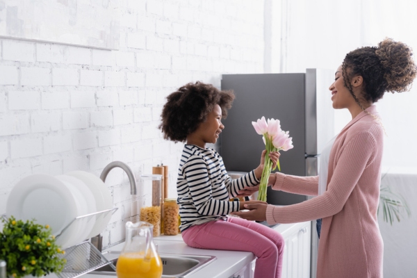 mom handing flowers to daughter sitting on the kitchen counter depicting springtime
