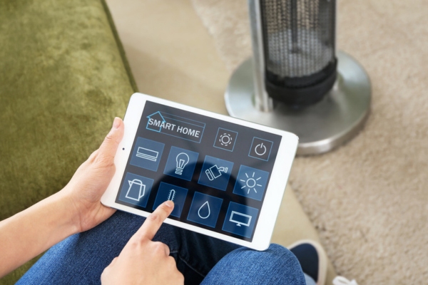 homeowner controlling home temperature using smart tablet depicting advancements in AC technology