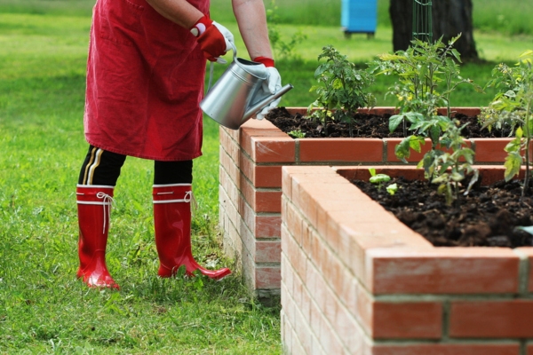 homeowner planting on a raised plant bed for unobstructed heating oil tank access