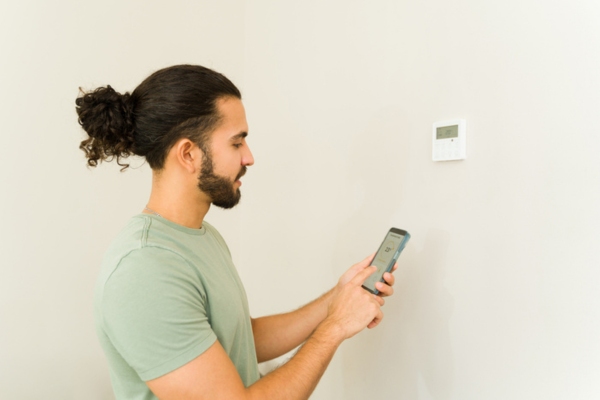 thermostat being controlled on smartphone depicting modern air conditioner features