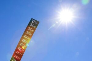 weather thermometer against blue sky and the sun