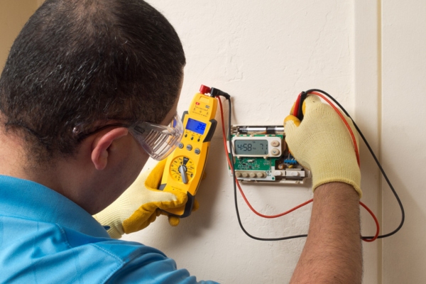 HVAC technician attending to a broken thermostat