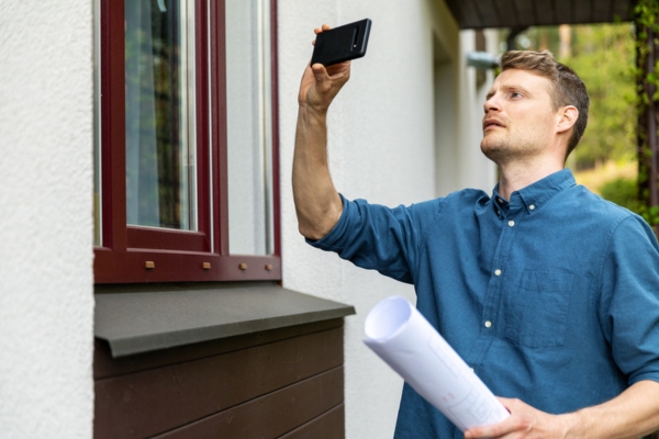 homeowner taking photo of window while inspecting for drafts & air leaks in house