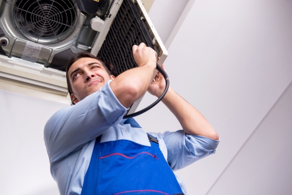 HVAC technician using a stethoscope listening to indoor air conditioner depicting diagnosing AC issues