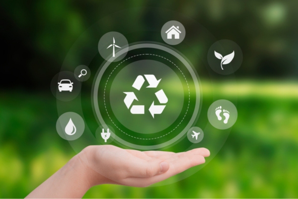 image of hand holding recycle & other icons against green background depicting environmental considerations