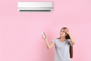 woman feeling warm while checking air conditioner due to weak air