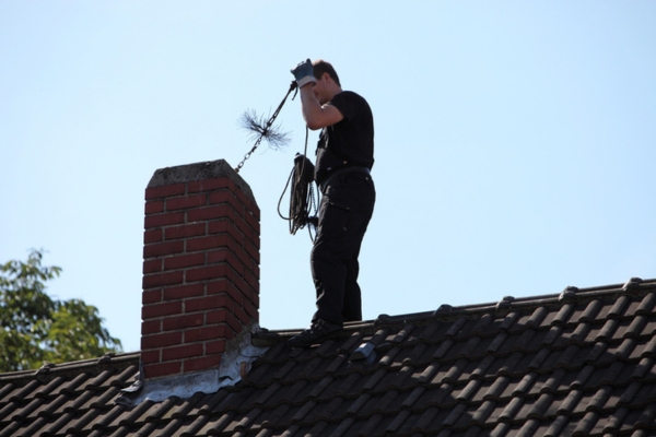 Handyman sweeping the chimney by inserting a brush