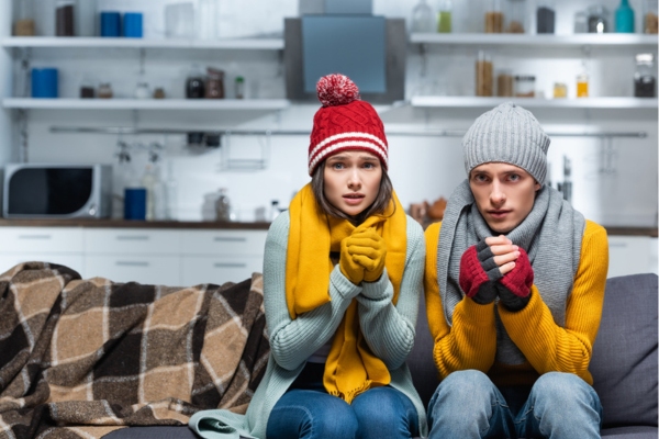 couple wearing full winter gear indoors due to HVAC neglect