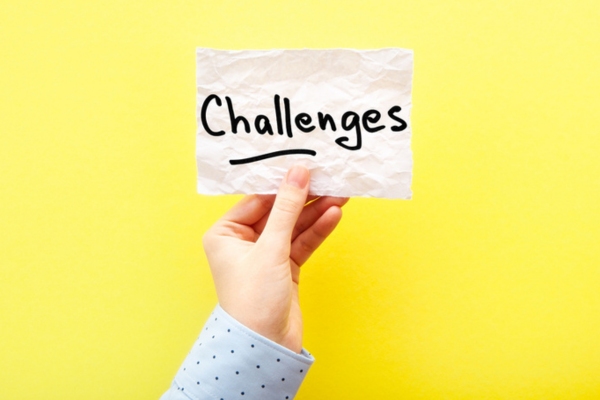 challenges written on a paper held up by a cropped woman's hand depicting hydronic heating