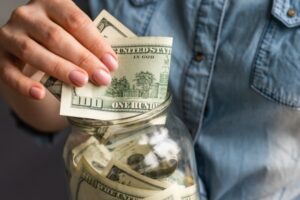 man putting one hundred dollar bill in a jar depicting fuel savings