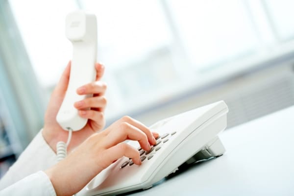 cropped view of a woman's hand calling a professional HVAC technician from a home phone