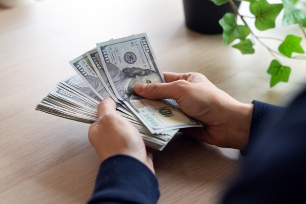 cropped view of a man counting money depicting cost analysis